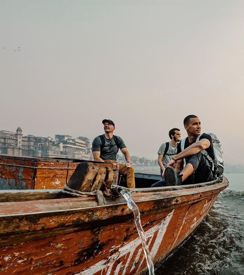 There men in a weathered rowboat, looking out at Indian sunset 